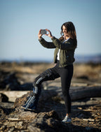 woman taking photo on the beach using both hands while wearing the freedom leg brace