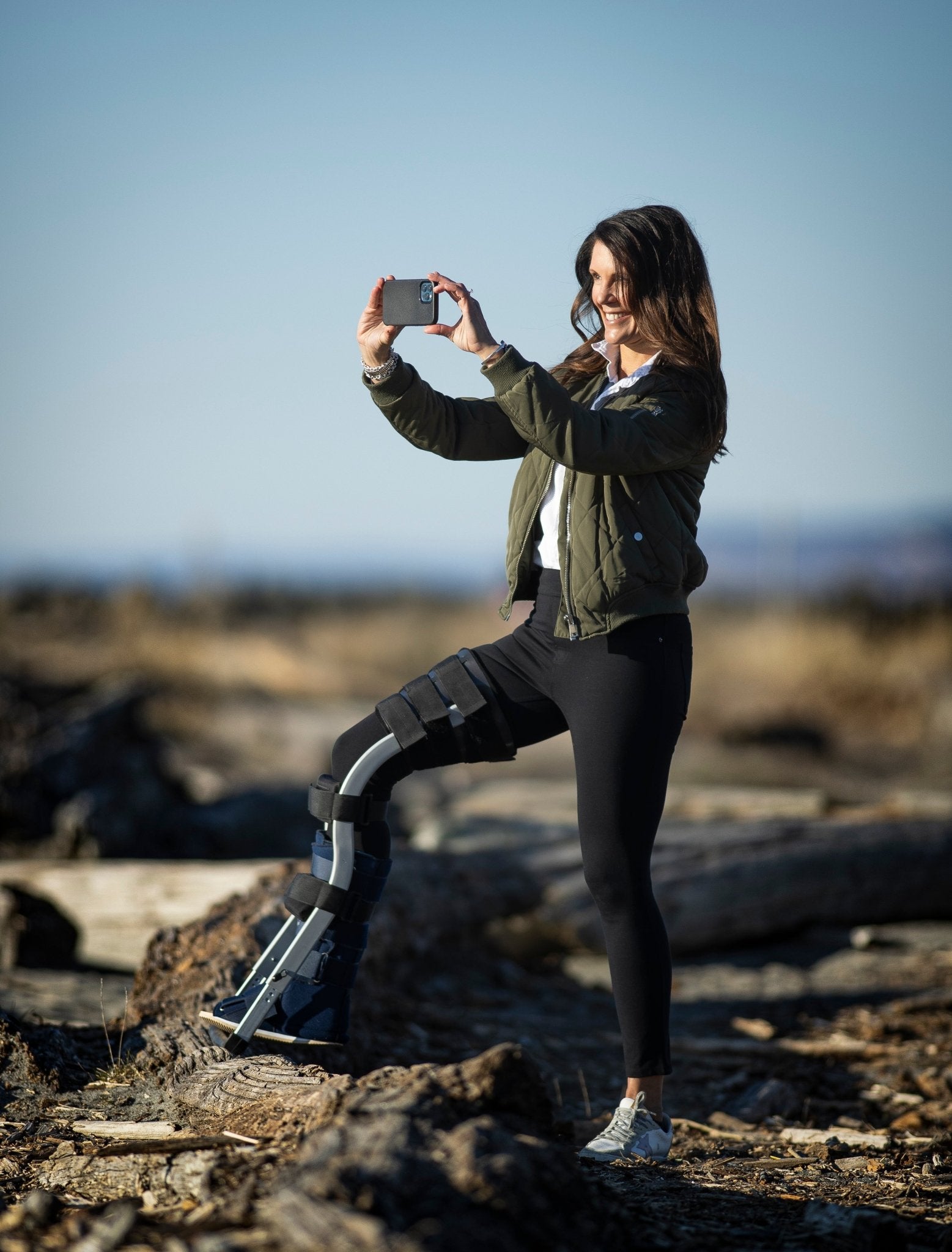 woman taking photo on the beach using both hands while wearing the freedom leg brace