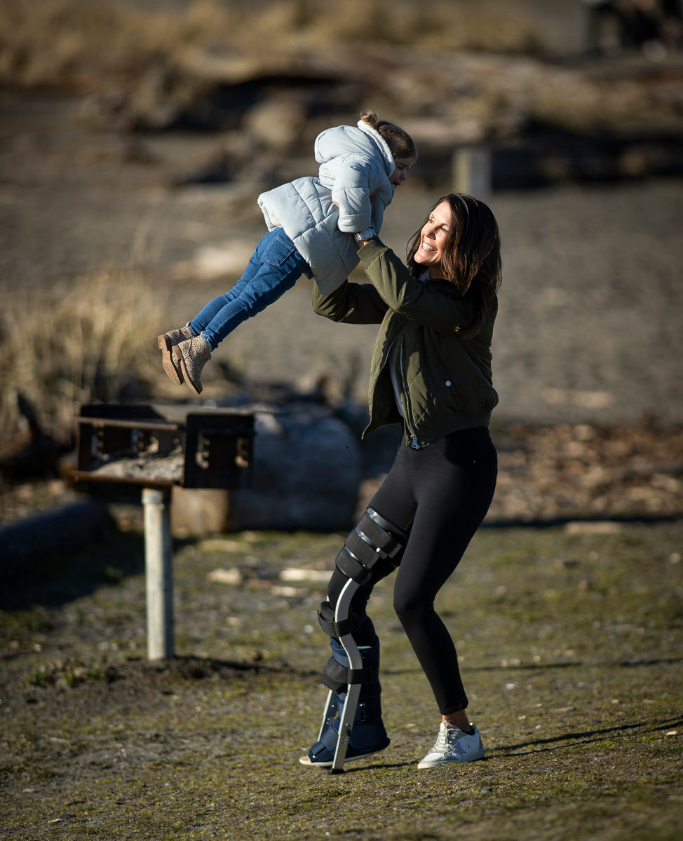 woman lifting up a child while wearing a leg brace
